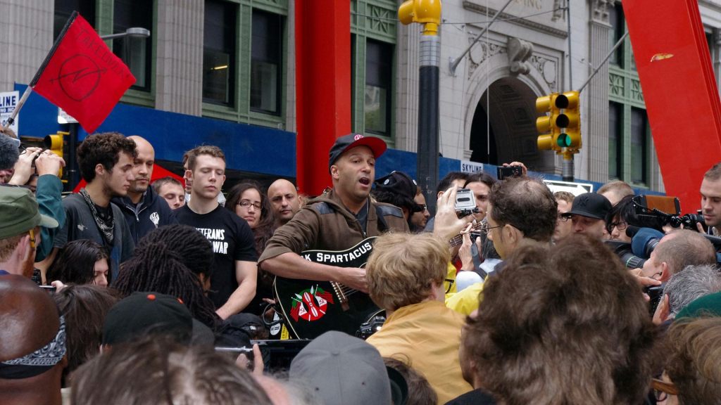 Rage Against the Machine grubunun gitaristi Tom Morello, New York’un Lower Manhattan bölgesindeki Equitable Building binasının önünde Occupy Wall Street protestocularıyla birlikte, 14 Ekim 2011. Fotoğraf: David Shankbone.